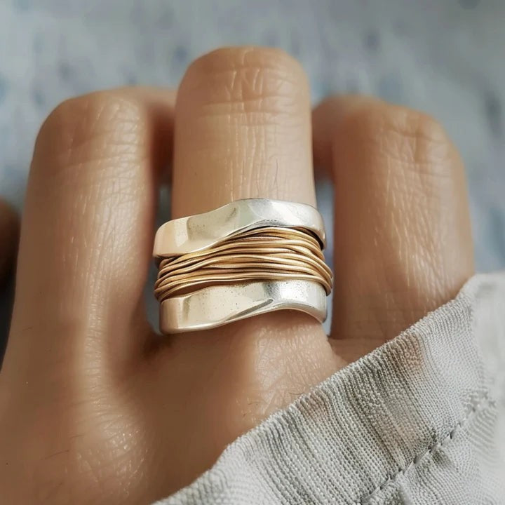 Breiter silberfarbener Ring mit goldfarbener Drahtwicklung am Finger