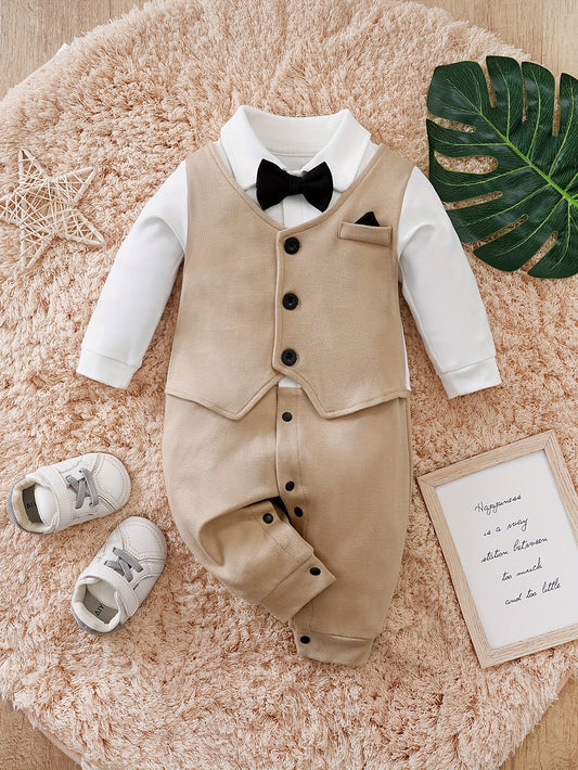 Beige-weißer Babystrampler mit schwarzer Fliege auf einem flauschigen Teppich