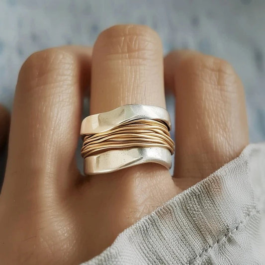 Breiter silberfarbener Ring mit goldfarbener Drahtwicklung am Finger