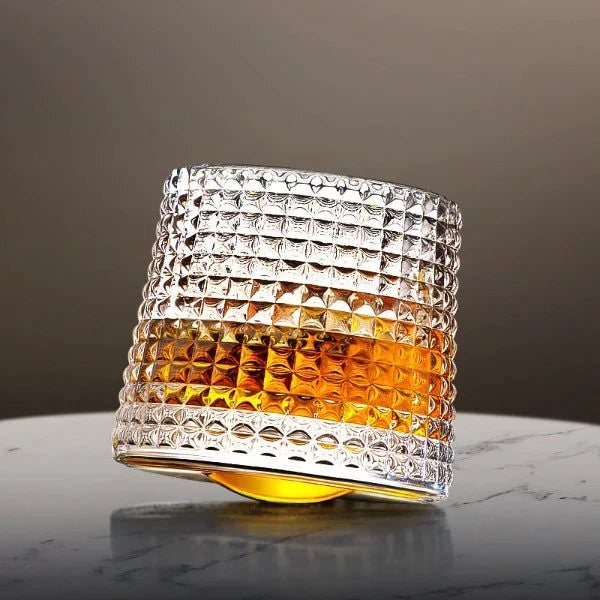 Gekipptes Whiskyglas mit Rautenrelief und Whisky auf einem Marmortisch