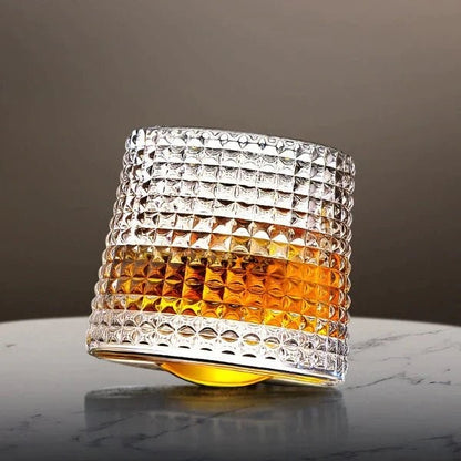 Gekipptes Whiskyglas mit Rautenrelief und Whisky auf einem Marmortisch