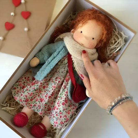Waldorfpuppe mit hellen Locken und Strickjacke in einer Geschenkbox