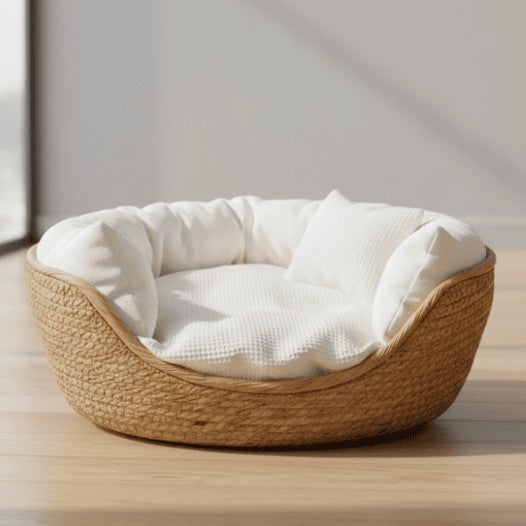 Rundes geflochtenes Katzenbett mit weißem Kissen auf einem Holzboden